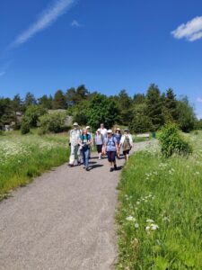 En grupp vuxna vandra längs en promenadväg på sommaren.