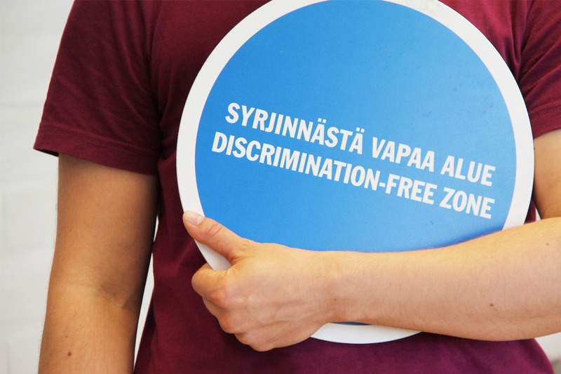 Ihminen pitää sylissä syrjinnästä vapaa alue -kylttiä.