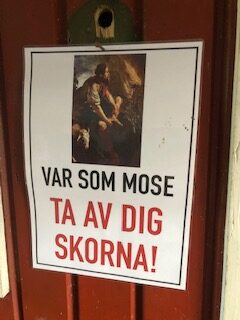 En skylt där det står "Var som Mose, ta av dig skorna" på dörren i en lägergård.